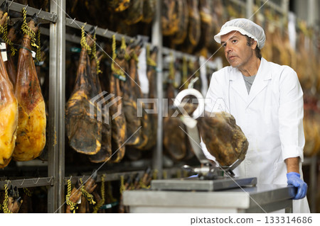 Man employee of hamon manufacturing workshop presents product using jamonero 133314686