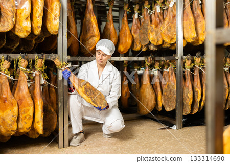 In jamon production shop, woman employee demonstrates final product 133314690