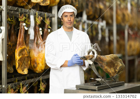 man presents jamon on a stand 133314702
