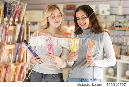 Two friends choose scented candles and sticks in perfume shop Two friends choose scented candles and sticks in perfume shop 133314707