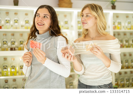 Two female friends choose scented handmade soap together in perfume shop Two female friends choose scented handmade soap together in perfume shop 133314715