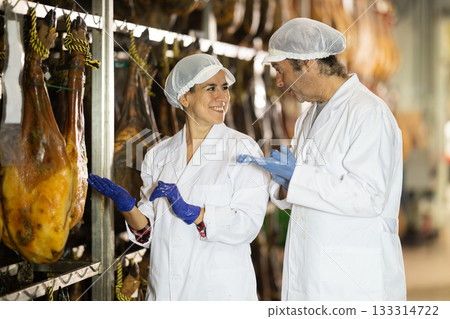 Man and female worker check jamon, discuss result 133314722