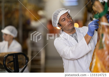 Man employee checks jamon. Quality control Man employee checks jamon. Quality control 133314723