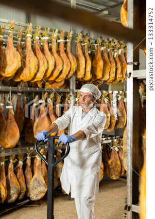 man factory worker prepares to load jamon onto a pallet truck 133314752