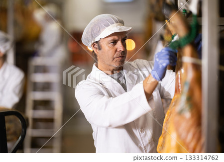 Man employee checks jamon. Quality control Man employee checks jamon. Quality control 133314762