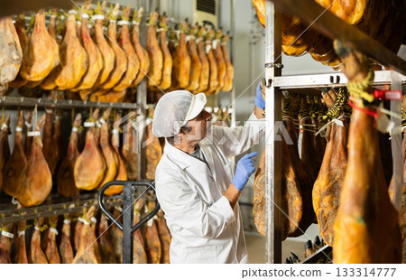 man checks the quality of ham in a factory man checks the quality of ham in a factory 133314777