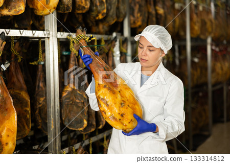 Girl employee checks jamon. Quality control 133314812
