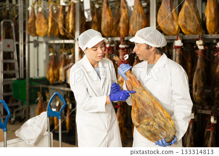 Two workers in the ham maturation shop discussing quality 133314813