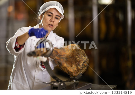 woman put the jamon on the bod and is preparing to cut 133314819