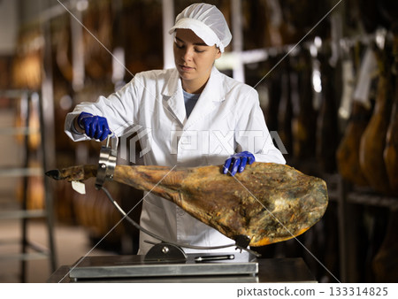 Girl factory worker places hamon in cutting device jamonero 133314825