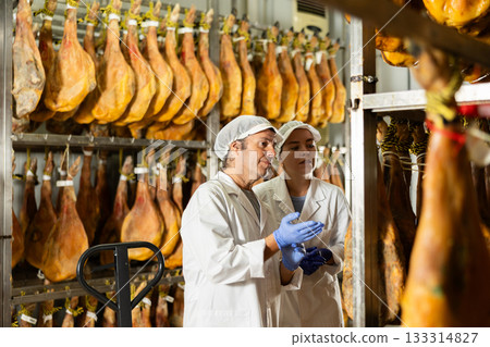 Two workers in the ham maturation shop discussing quality 133314827