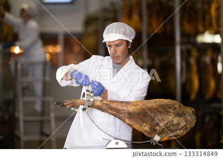 Man preparing to slice jamon on a stand 133314849