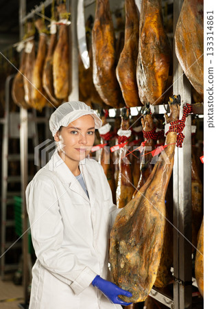 female worker checks the quality of jamon in a factory female worker checks the quality of jamon in a factory 133314861
