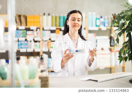 Middle-aged female pharmacist offering ointment in box Middle-aged female pharmacist offering ointment in box 133314863
