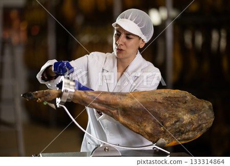 woman put the jamon on the bod and is preparing to cut 133314864