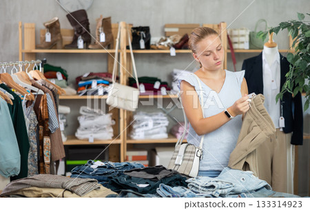 Woman standing in the store and choosing pants and shorts Woman standing in the store and choosing pants and shorts 133314923