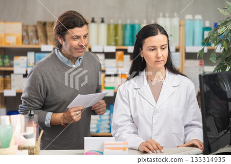 man with a medical prescription consults a pharmacist 133314935