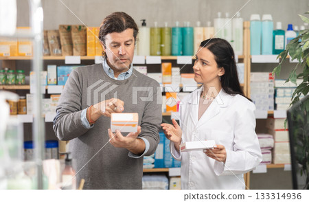 Middle-aged man choosing pills in box while pharmacist offering in drugstore 133314936