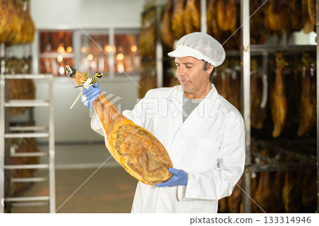 Man employee checks jamon. Quality control 133314946