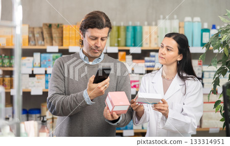 man scans a package with pills in a pharmacy on a mobile barcode 133314951