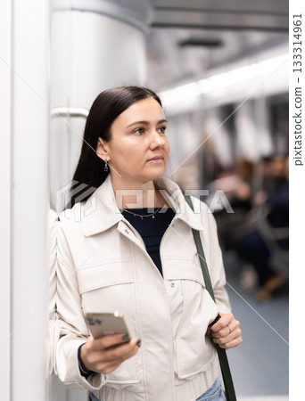 Woman with phone stand in metro carriage. Woman with phone stand in metro carriage. 133314961