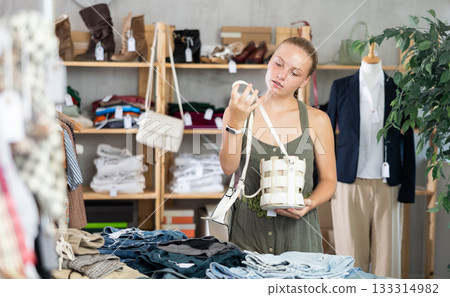 Teenage girl choosing handbag in clothing store Teenage girl choosing handbag in clothing store 133314982