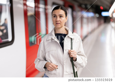 Female passenger awaits the metro train at arrival station 133315019
