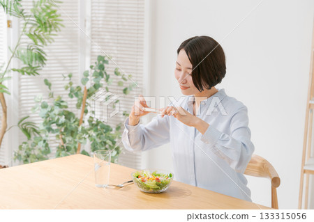 A woman taking a photo of a salad with her smartphone A woman taking a photo of a salad with her smartphone 133315056
