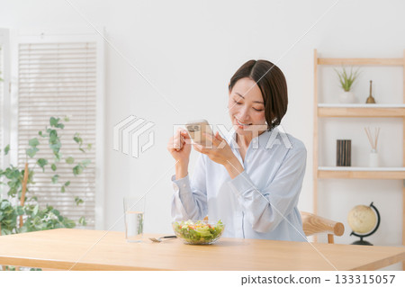 A woman taking a photo of a salad with her smartphone A woman taking a photo of a salad with her smartphone 133315057