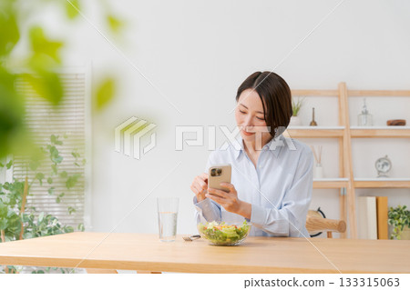 A woman taking a photo of a salad with her smartphone A woman taking a photo of a salad with her smartphone 133315063