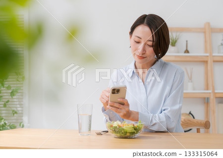 A woman taking a photo of a salad with her smartphone 133315064