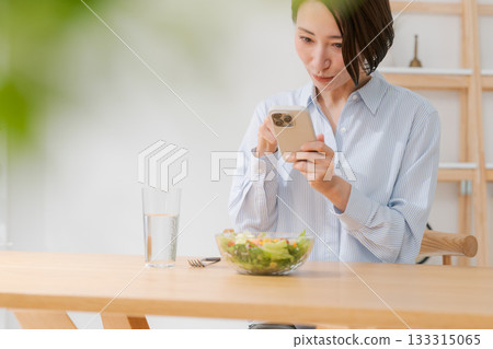 A woman taking a photo of a salad with her smartphone A woman taking a photo of a salad with her smartphone 133315065
