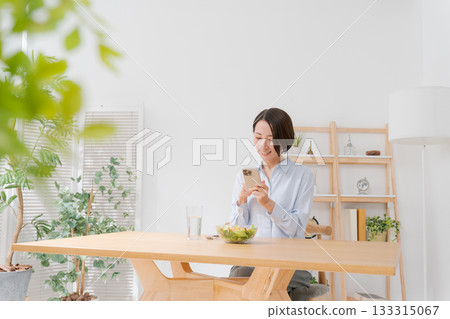 A woman taking a photo of a salad with her smartphone 133315067