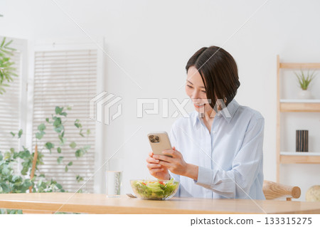 一位女士正在用智慧型手機拍攝沙拉的照片。 133315275