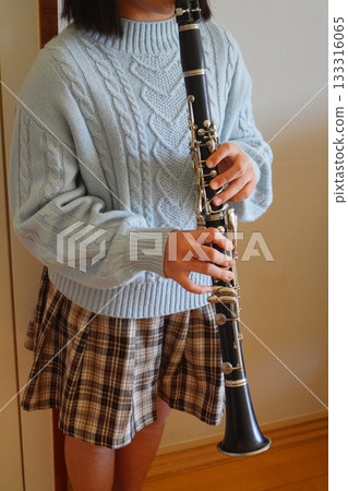 一張垂直版照片,照片中一個小孩穿著淺藍色麻花針織衫,手上拿著單簧管。 一張垂直版照片,照片中一個小孩穿著淺藍色麻花針織衫,手上拿著單簧管。 133316065