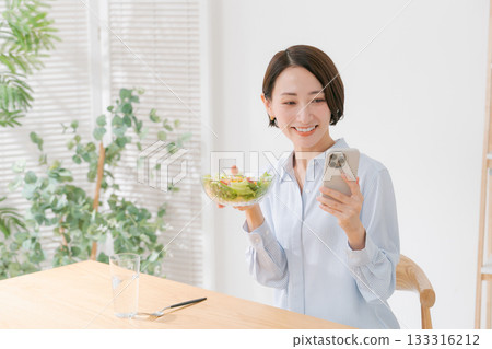A woman with a smartphone and salad 133316212