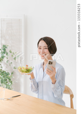 一位女士拿著智慧型手機和沙拉 133316253