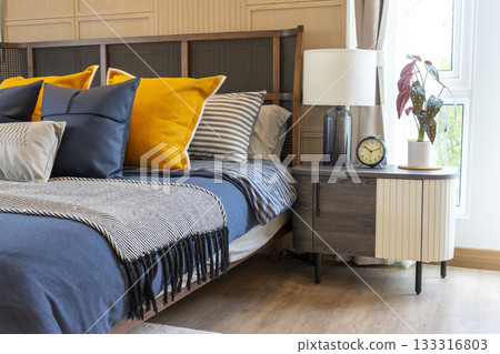 Interior of yellow and blue pillow on cozy modern bedroom with carpet and side table lamp. 133316803