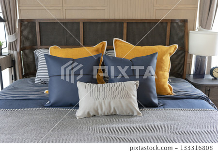 Interior of yellow and blue pillow on cozy modern bedroom with carpet and side table lamp. 133316808