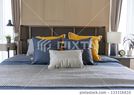 Interior of yellow and blue pillow on cozy modern bedroom with carpet and side table lamp. 133316810