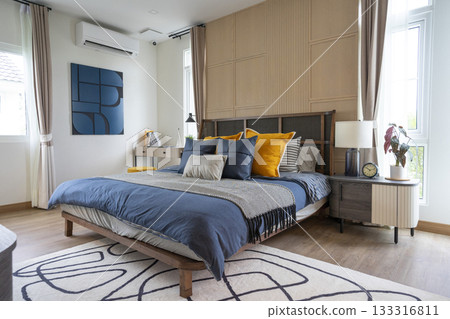 Interior of yellow and blue pillow on cozy modern bedroom with carpet and side table lamp. 133316811