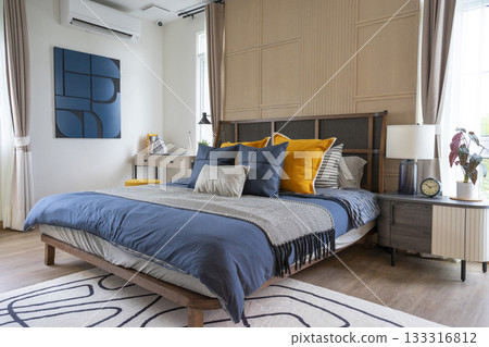 Interior of yellow and blue pillow on cozy modern bedroom with carpet and side table lamp. 133316812
