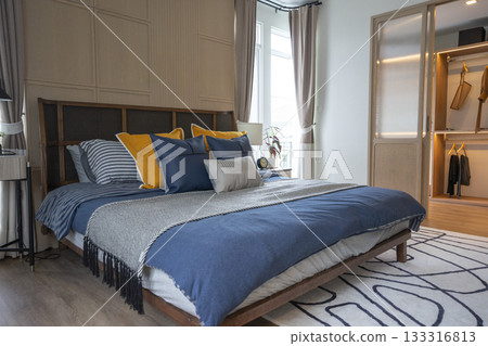 Interior of yellow and blue pillow on cozy modern bedroom with carpet and side table lamp. 133316813