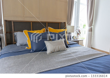 Interior of yellow and blue pillow on cozy modern bedroom with carpet and side table lamp. 133316814