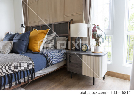 Interior of yellow and blue pillow on cozy modern bedroom with carpet and side table lamp. 133316815