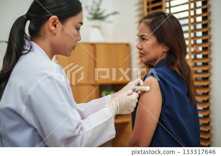 doctor holding syringe and making injection vaccine to patient 133317646