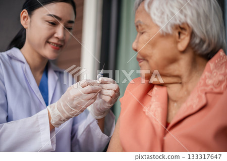 doctor holding syringe and making injection vaccine to senior woman doctor holding syringe and making injection vaccine to senior woman 133317647