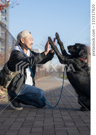 一個男人和他的寵物狗擊掌——這一幕展現了友誼和信任。 一個男人和他的寵物狗擊掌——這一幕展現了友誼和信任。 133317820