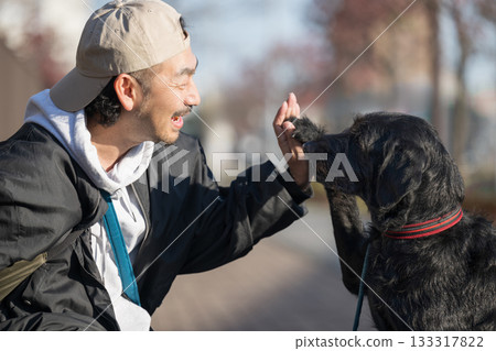 A man enjoying a high-five with his pet dog - a communication scene that evokes friendship and trust A man enjoying a high-five with his pet dog - a communication scene that evokes friendship and trust 133317822