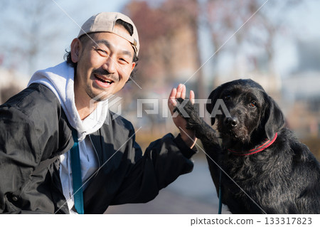A man enjoying a high-five with his pet dog - a communication scene that evokes friendship and trust 133317823